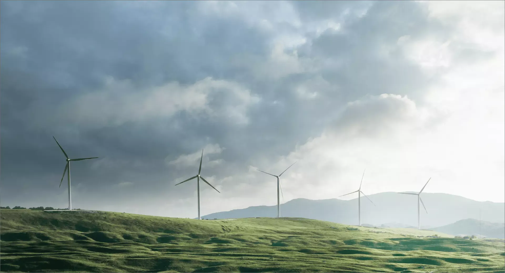 Wind turbines on green hills under a cloudy sky